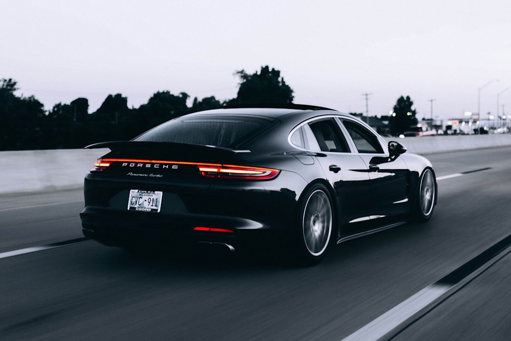 Um Porsche Panamera preto em andamento numa autoestrada, ao fim do dia